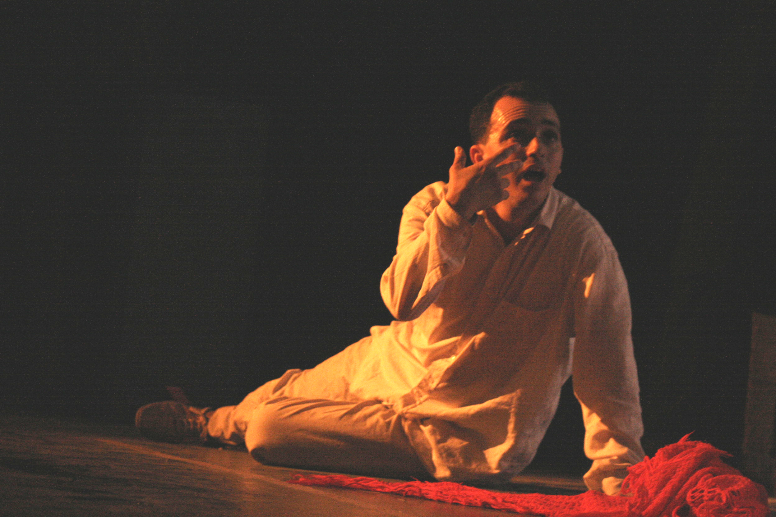 Interprète assis sur scène sous un éclairage doré — archives théâtre, 2007